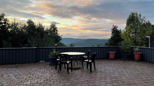An outdoor patio with a round table and chairs, surrounded by potted plants and a brick floor. - Schönblick B8 House · Mountain Charm with a View of Nature (Schöfweg)