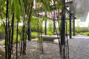 A covered outdoor area with bamboo plants, a gravel path, and a concrete bench. - Bukit Bintang Lalaport Designer Studio KLCC View (Kuala Lumpur)