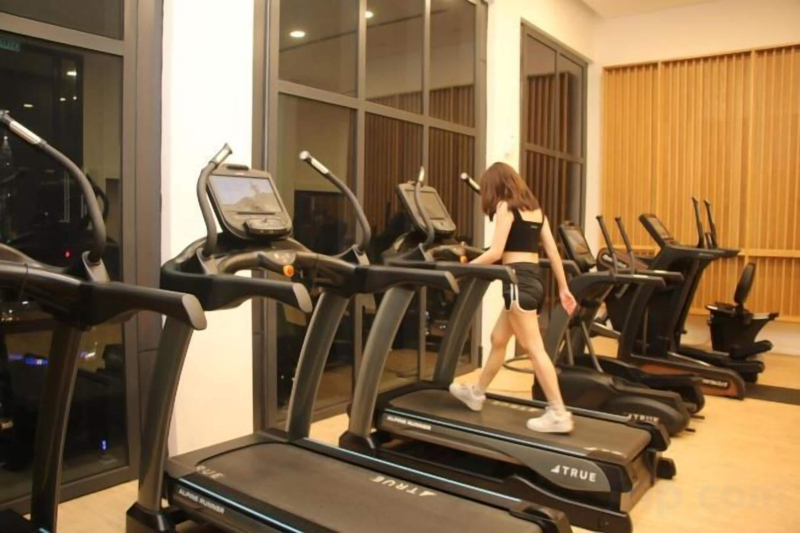 A gym with treadmills and a person walking on one.