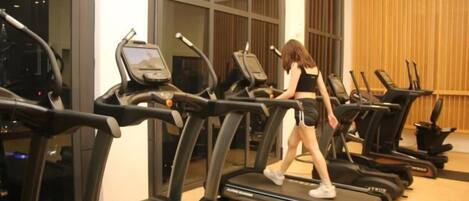 A gym with treadmills and a person walking on one.