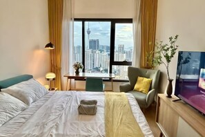 Habitación de hotel con cama, escritorio, silla, televisor y vistas a la ciudad.