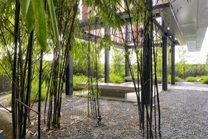 A covered outdoor area with bamboo plants, a gravel path, and a concrete bench. - Bukit Bintang Lalaport Designer Studio KLCC View (Kuala Lumpur)