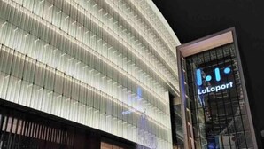 Un edificio moderno con un llamativo letrero 'LaLaport', con fachada de vidrio y una fuente en la base.