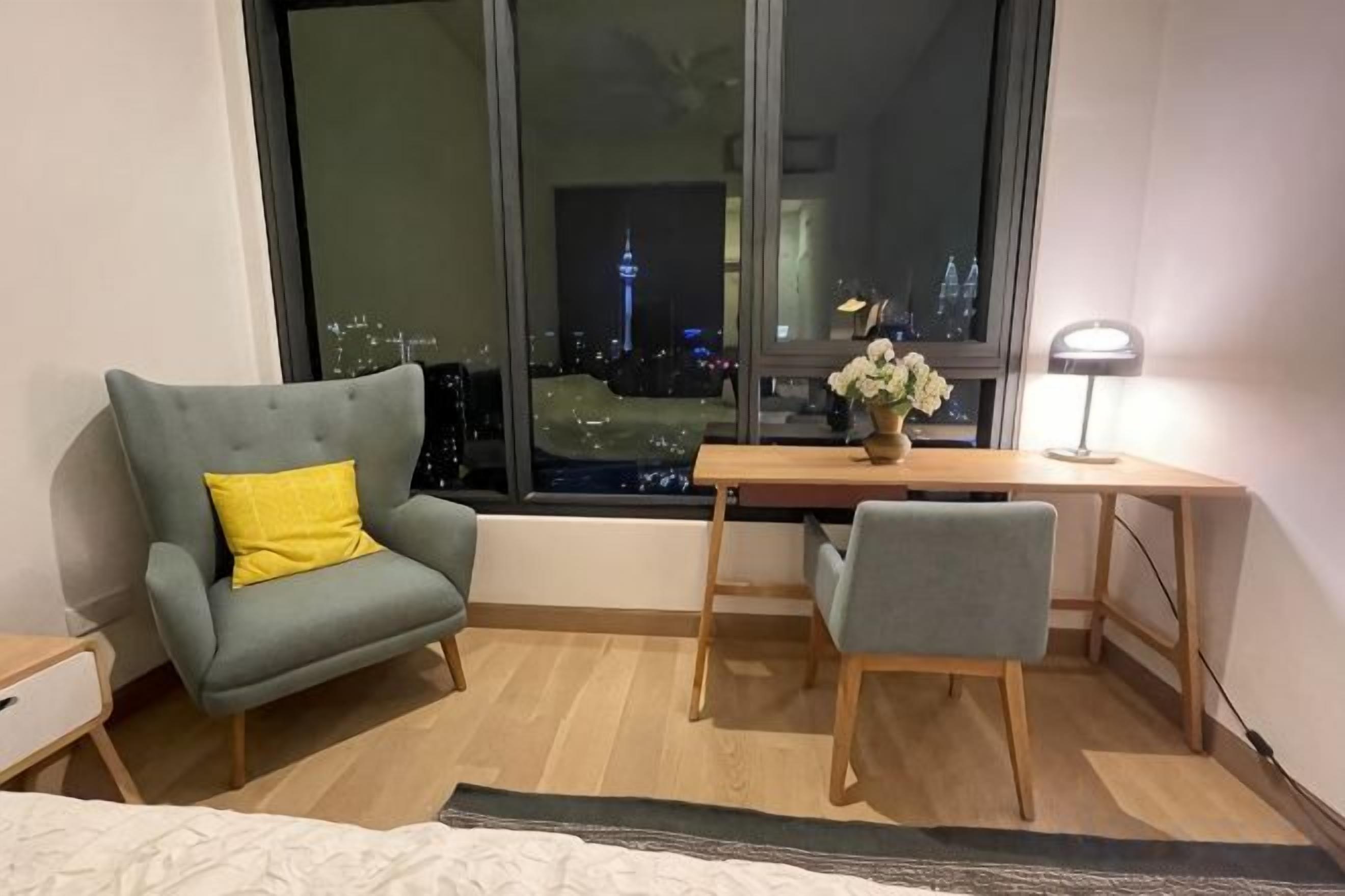 A room with a bed, a desk, a chair, and a window with a city view.