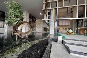 En moderne lobby med et centralt vandfald, en spiralformet skulptur og en trappe.