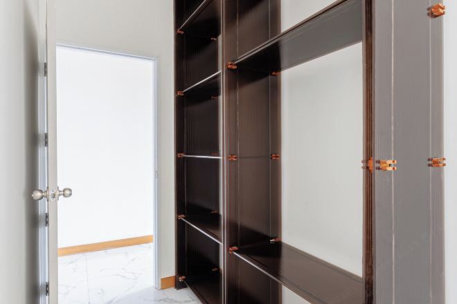 A room with a large wardrobe, a door, and a tiled floor.