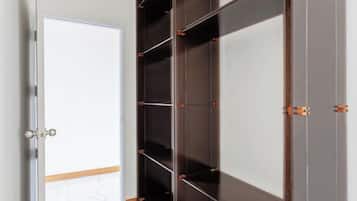 A room with a large wardrobe, a door, and a tiled floor.