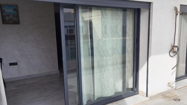 A modern room with a sliding glass door leading to a balcony, a power outlet, and a small window. - Jinhui Hotel (Casablanca)