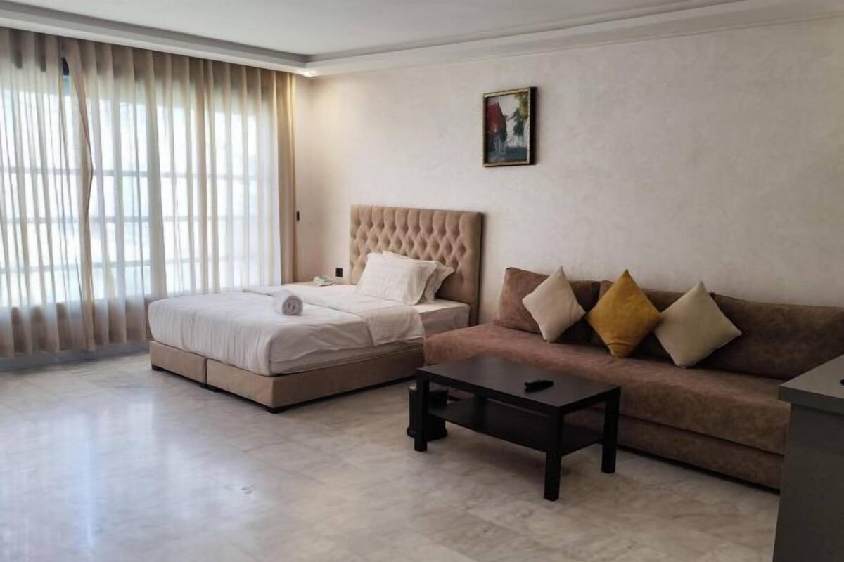 Un dormitorio con cama, sofá, mesa de centro y un cuadro en la pared.