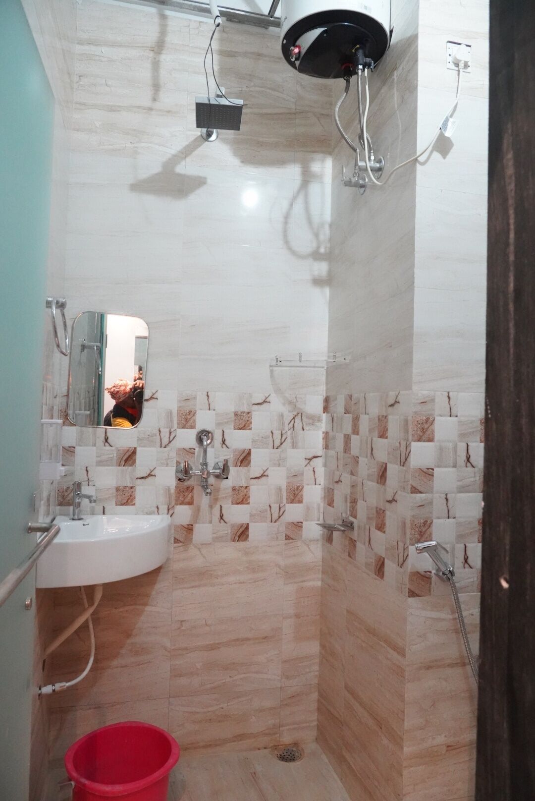 A bathroom with a sink, mirror, shower, and tiled walls.