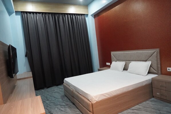 A hotel room with a bed, a TV, a desk, and a wardrobe. - Viraj International Hotel (Pindra)