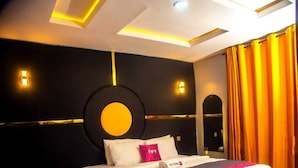 A modern hotel room with a large bed, a circular wall decoration, and a unique ceiling design. - Ivy Hotel Epe (Epe)