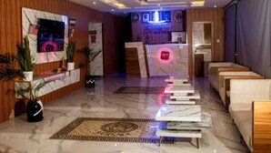 A hotel lobby with a reception desk, seating area, and a TV screen displaying a welcome message. - Ivy Hotel Epe (Epe)
