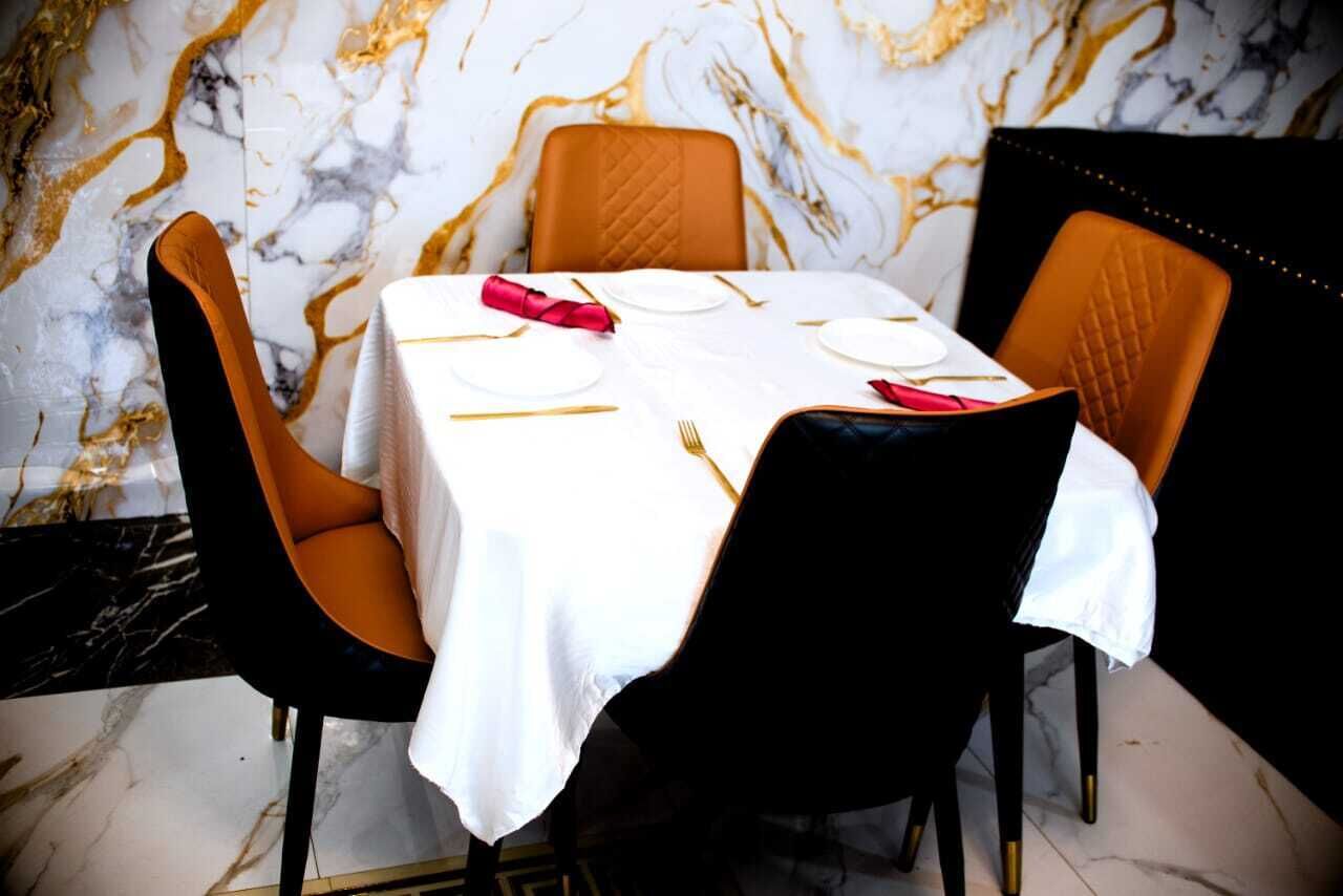 Ein Esstisch, gedeckt mit weißer Tischdecke, goldbestecktem Geschirr und roten Servietten.