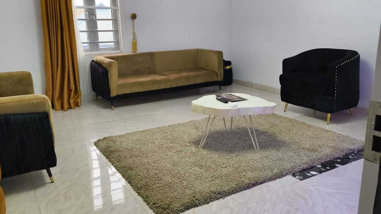 Un salon avec un canapé beige, un fauteuil noir et une table basse blanche.