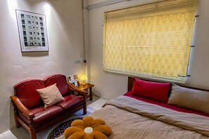 A bedroom with a bed, a red sofa, a small table with a lamp, and a window with blinds. - Little India - Guesthouse (8 mins walk to Jonker Street) (Melaka)