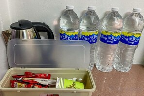 A kitchen area with a stainless steel kettle, a knife block, and a plastic container with food items. There are four bottles of water labeled 'One' on a countertop. - Little India - Guesthouse (8 mins walk to Jonker Street) (Melaka)