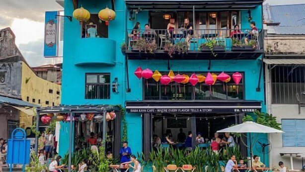 Un bâtiment d’un bleu éclatant, avec un café appelé « Baba Kaya Café » situé au rez-de-chaussée.