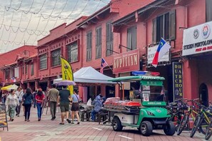 A street scene with pedestrians, a street vendor cart, and a building with signage. - Little India - Guesthouse (8 mins walk to Jonker Street) (Melaka)
