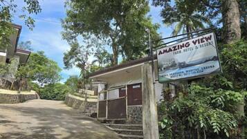 A sign for 'AMAZING VIEW FARM HOTEL & RESORT' with a view of the surrounding landscape.