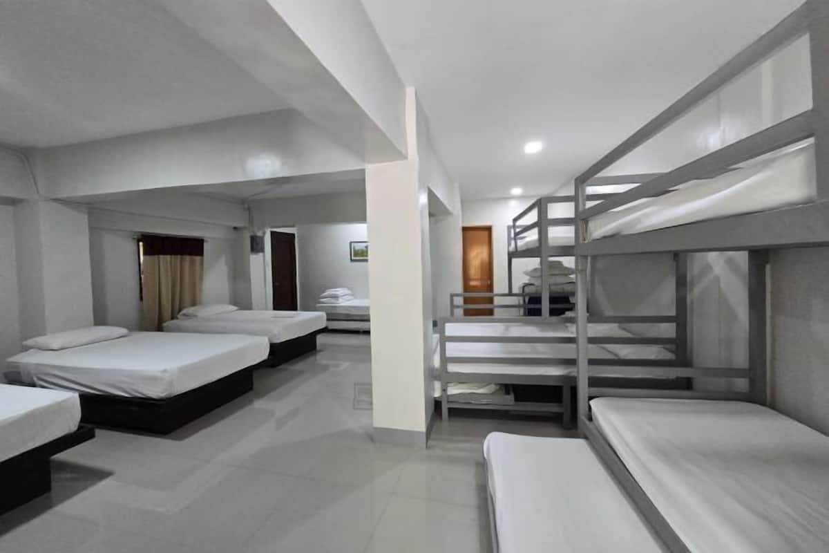 Habitación de hotel con literas, una cama individual y un baño con ducha e inodoro.