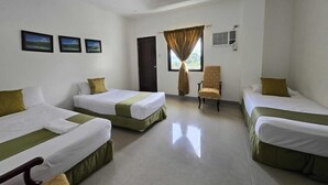 A hotel room with three single beds, a chair, a window with curtains, and three framed pictures on the wall. - Amazing View Mountain Resort Laguna (Mabitac)