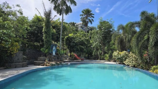 A swimming pool surrounded by lush greenery and a stone wall. - Amazing View Mountain Resort Laguna (Mabitac)
