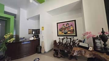 Un área de recepción con un mostrador de madera, un cuadro enmarcado encima y un banco de madera decorativo.