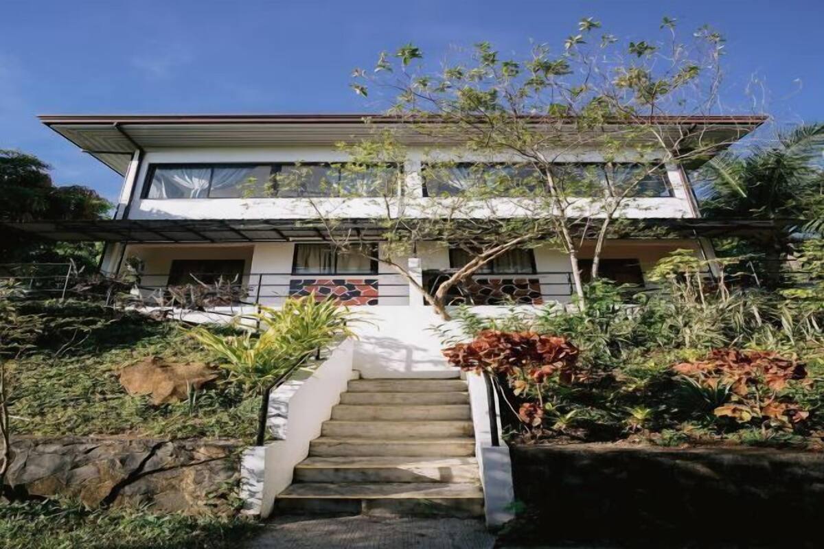 Una casa moderna de dos pisos con una escalera que lleva a la entrada.