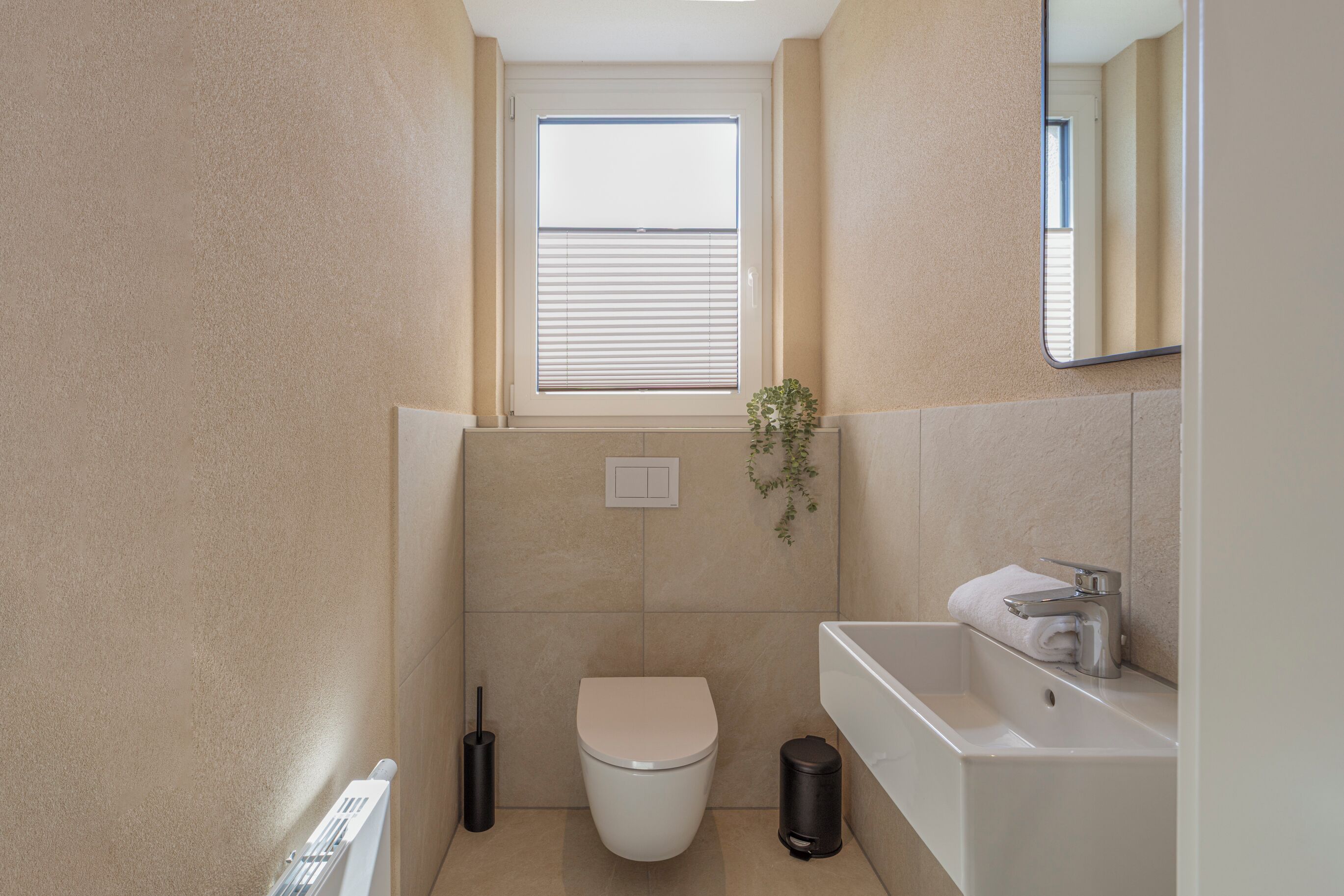 A compact bathroom with a toilet, a sink, and a window above the toilet.