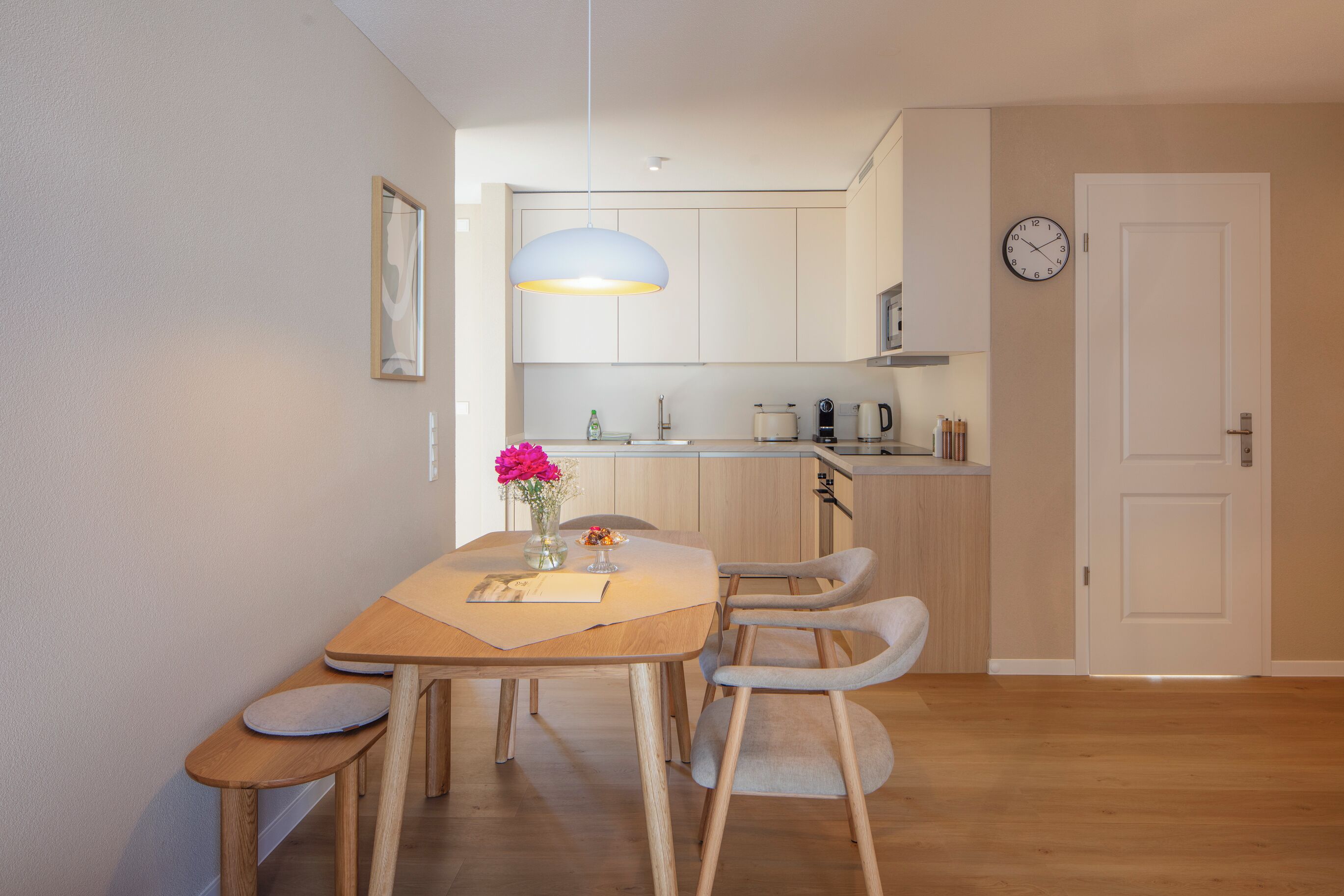 Eine moderne Küche mit einem Holzespeisetisch, Stühlen und einer Pendelleuchte.