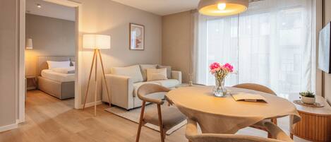 A modern living room with a round dining table, a sofa, and a lamp.