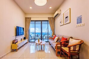 Ein modernes Wohnzimmer mit Sofa, Sesseln, Couchtisch, Fernseher und einem Balkon mit Blick.