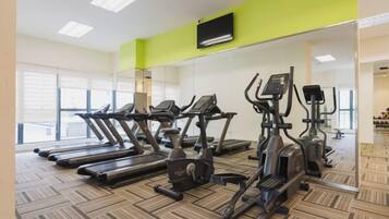 A gym with treadmills, elliptical machines, and a mirrored wall.