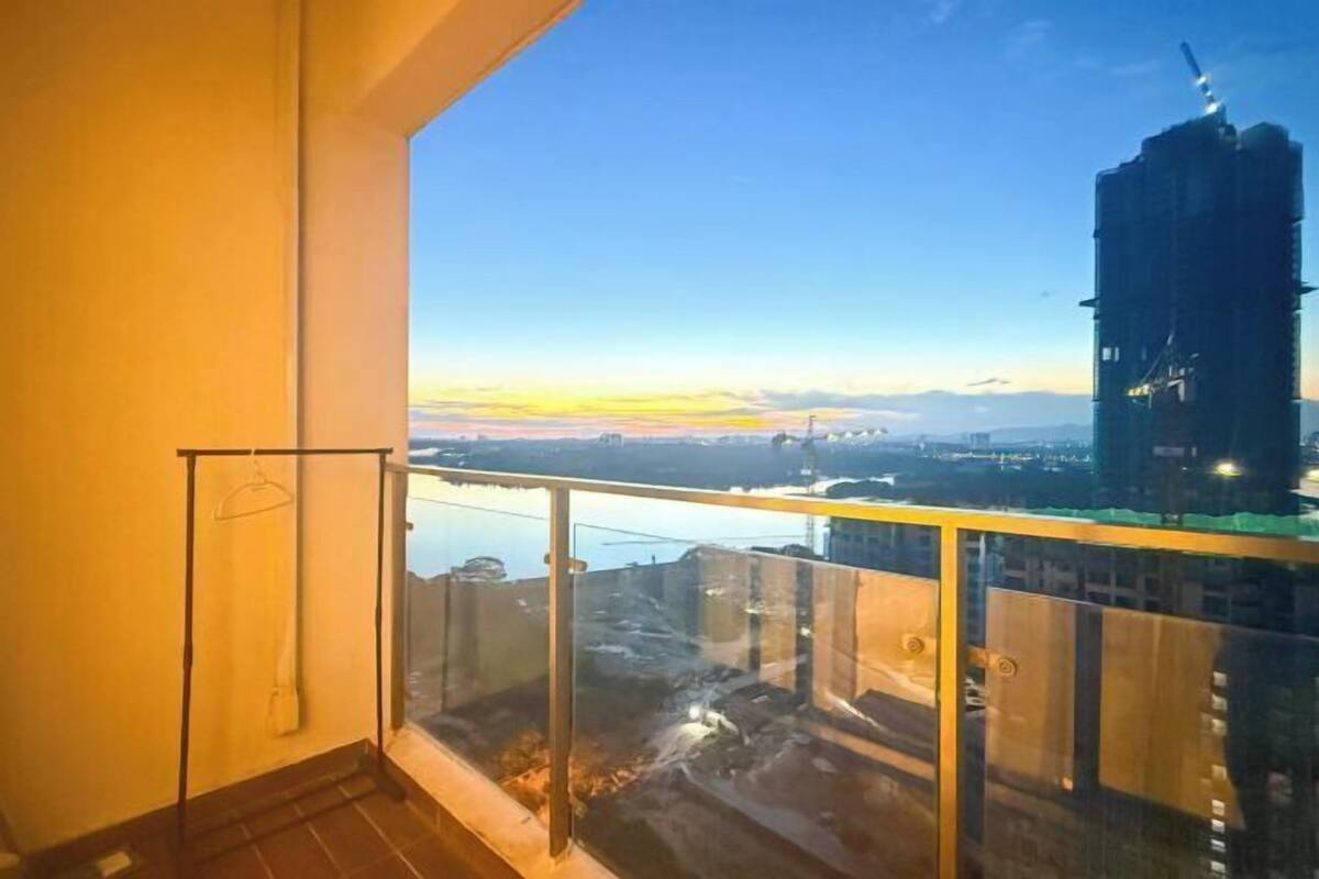 A balcony with a glass railing overlooking a cityscape at dusk.