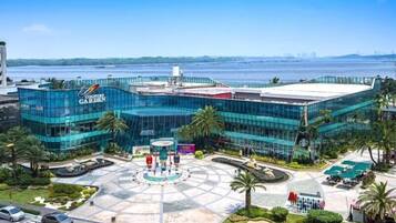 A modern building with a glass facade, a central courtyard with a fountain, and a view of the water body in the background.
