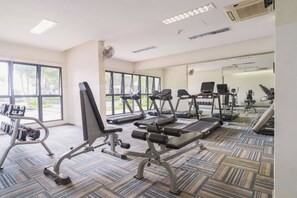 Une salle de sport équipée de tapis de course, de vélos elliptiques et de poids libres.