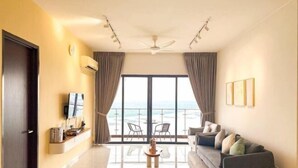 A modern living room with a sofa, a coffee table, and a view of the sea through large windows. - Danga Bay Country Garden by RR JBcity (Johor Bahru)
