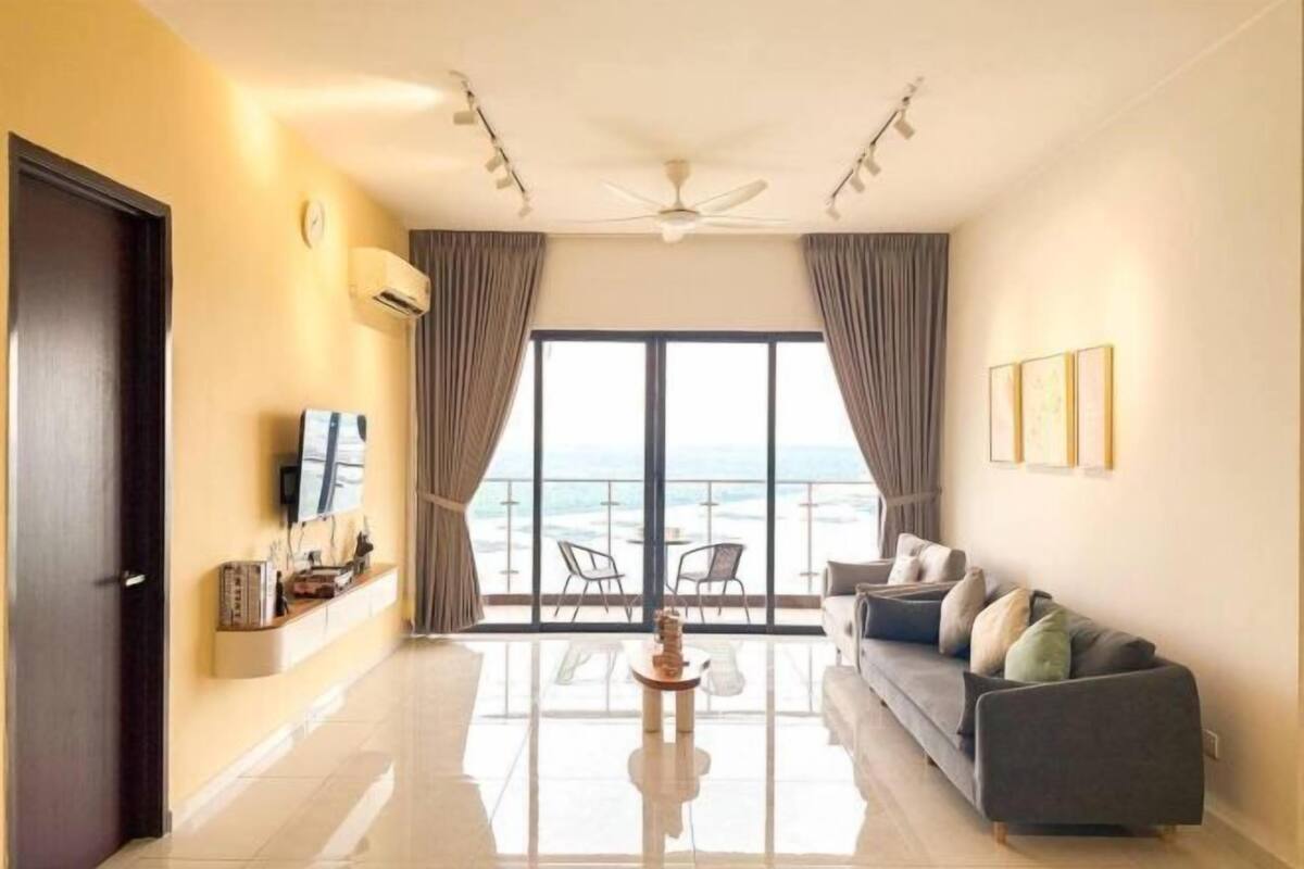A modern living room with a sofa, a coffee table, and a view of the sea through large windows.