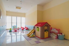 A playroom with a slide, playhouse, and toys.