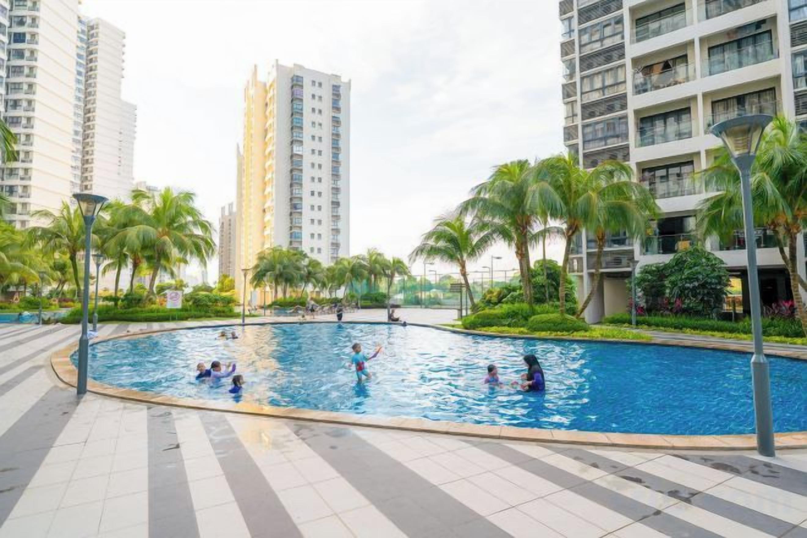 A swimming pool surrounded by palm trees and modern buildings.