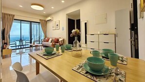 A modern hotel room with a dining area, a sofa, and a view of the city. - Danga Bay Country Garden by RR JBcity (Johor Bahru)