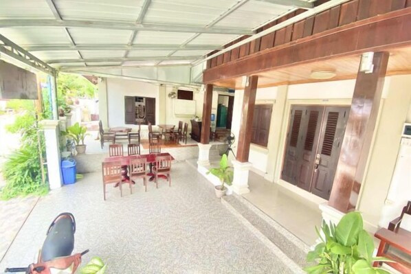 A covered outdoor area with a dining table and chairs, potted plants, and a grill. - Xuan Keo Place House 2 (Luang Prabang)