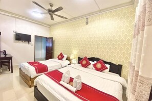 Ein Hotelzimmer mit zwei Betten, einem Deckenventilator, einem Fernseher und einem Schreibtisch.