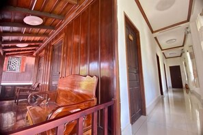 A wooden interior with a polished floor, a wooden bench, and a hallway leading to a door. - Xuan Keo Place House 2 (Luang Prabang)