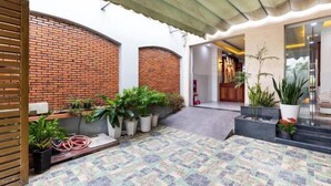 A courtyard with a brick wall, potted plants, and a tiled floor. - Luxury Vuon Lai Hotel (Ho Chi Minh City)
