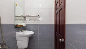 A bathroom with a white sink, a glass shelf with toiletries, and a wooden door. - Luxury Vuon Lai Hotel (Ho Chi Minh City)