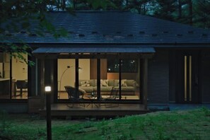 A modern house with a glass-enclosed porch, a dining area, and a living room with a sofa and chairs. - Fandina Fujiwara (Tsumagoi)