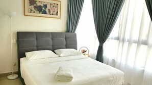 A neatly made bed with pillows and a folded towel, a bedside lamp, and a framed picture on the wall. - Conezion at Putrajaya #IOI CITY MALL #7 Pax #NEW (Serdang)
