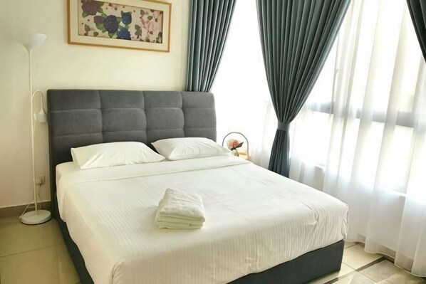 A neatly made bed with pillows and a folded towel, a bedside lamp, and a framed picture on the wall. - Conezion at Putrajaya #IOI CITY MALL #7 Pax #NEW (Serdang)